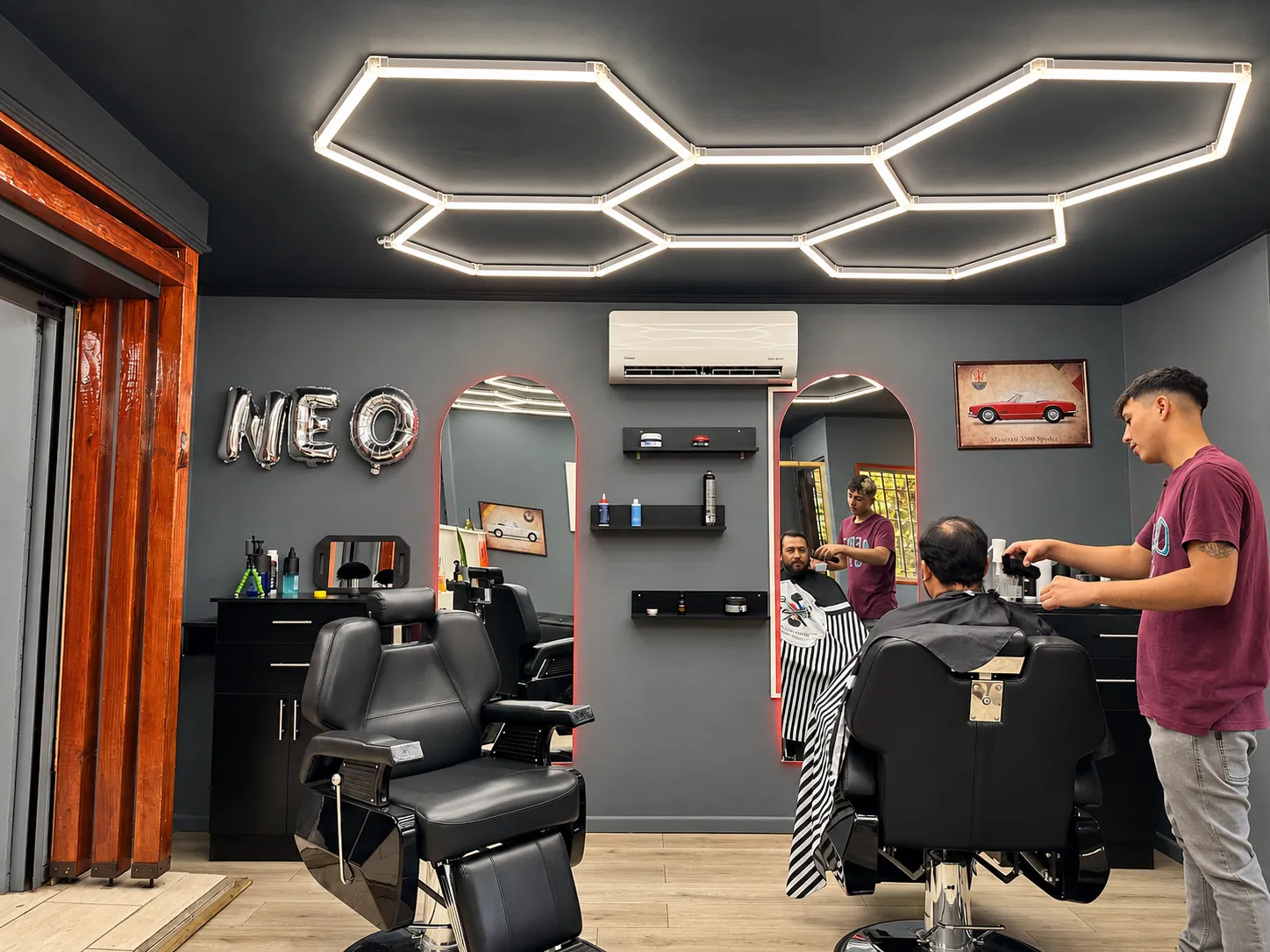 Interior del estudio Neo, con sus barberos trabajando y luces geométricas