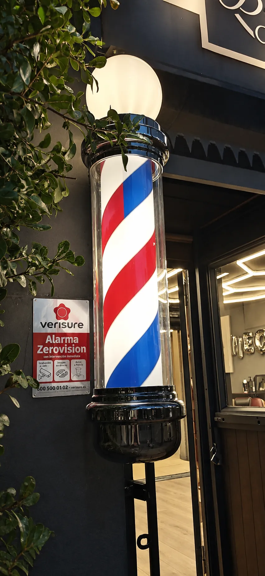 Poste de barbería iluminado junto a la entrada de Neo Barber Studio